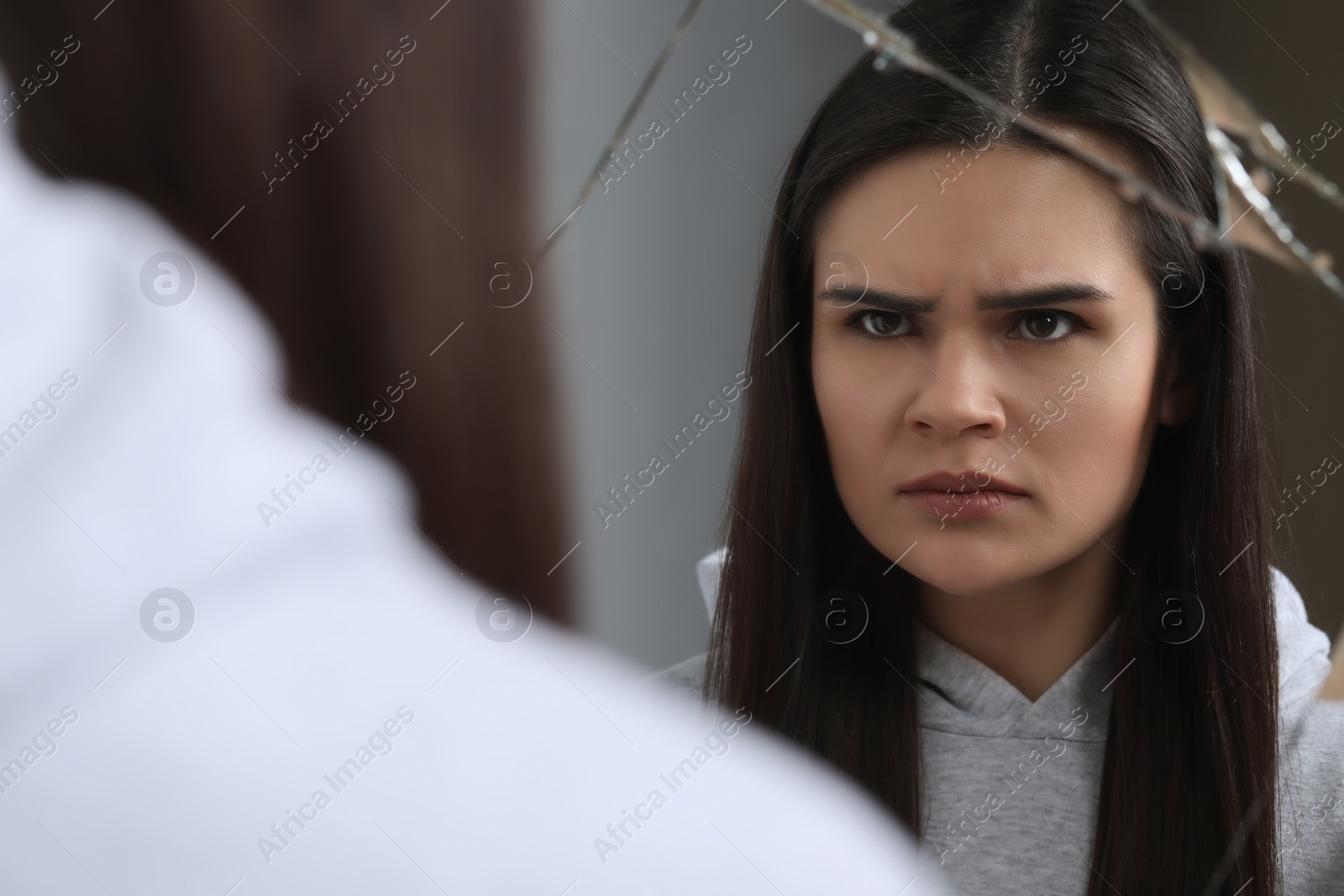 Photo of Depressed young woman suffering from mental problems near broken mirror