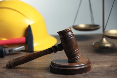 Construction and land law concepts. Gavel, scales of justice, hard hat, pliers and hammer on wooden table, closeup