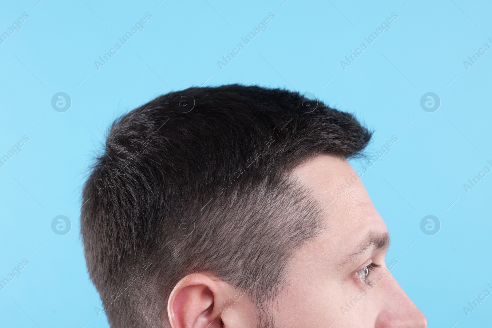 Photo of Man with healthy hair on light blue background, closeup