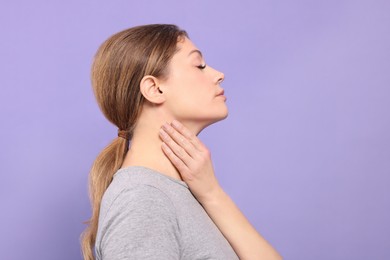 Woman suffering from sore throat on violet background