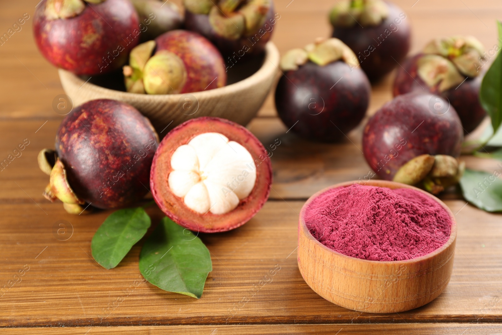 Photo of Purple mangosteen powder and fruits on wooden table