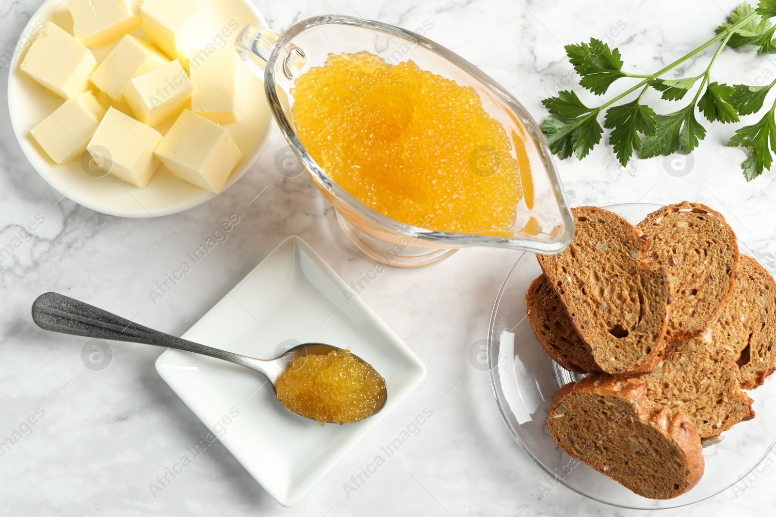 Photo of Fresh pike caviar, butter, bread and parsley on white marble table, flat lay