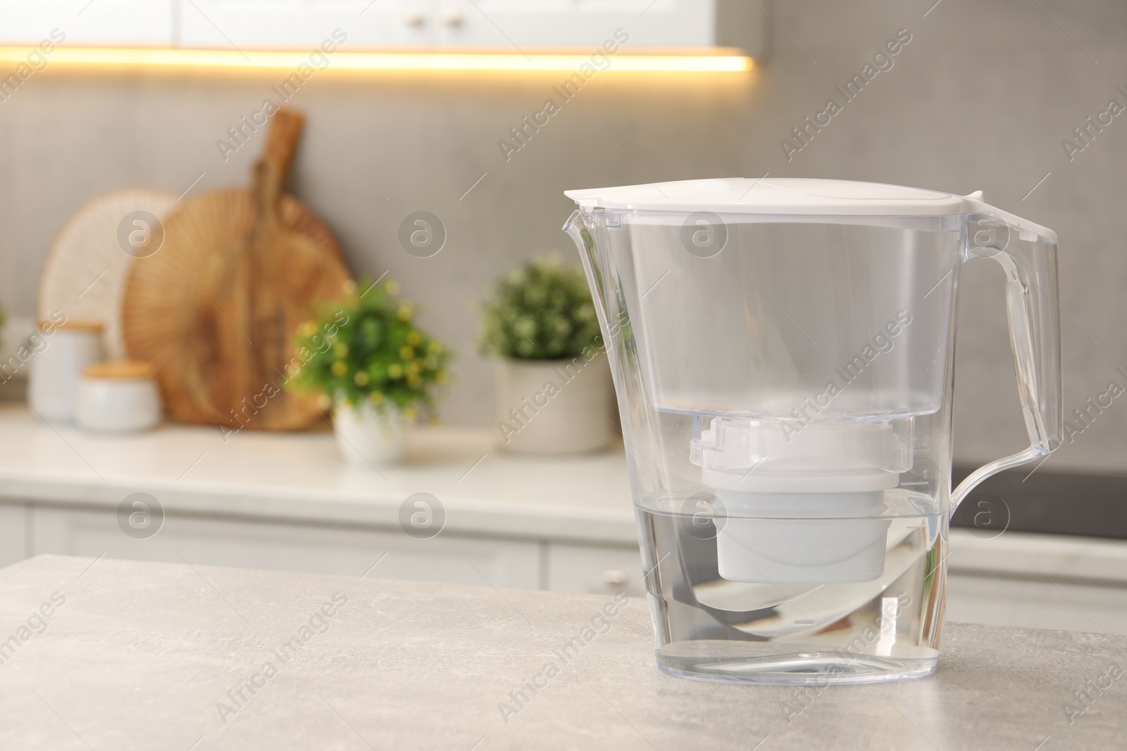 Photo of Water filter jug on light grey table in kitchen, space for text