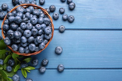 Photo of Tasty fresh blueberries on blue wooden table, flat lay. Space for text