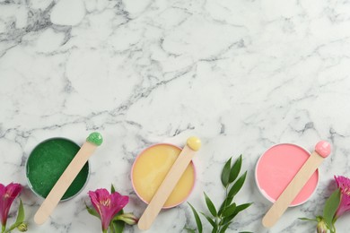 Photo of Spatula with different types of wax and flowers on white marble table, flat lay. Space for text
