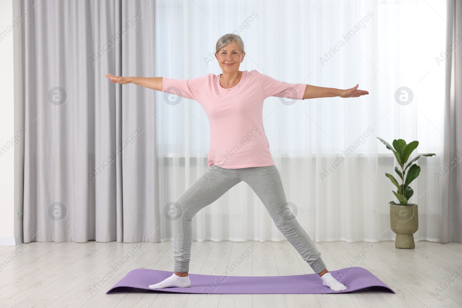 Photo of Happy senior woman practicing yoga on mat at home