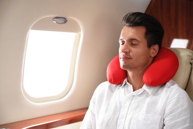 Image of Handsome man with neck pillow sleeping during flight. Ait travel