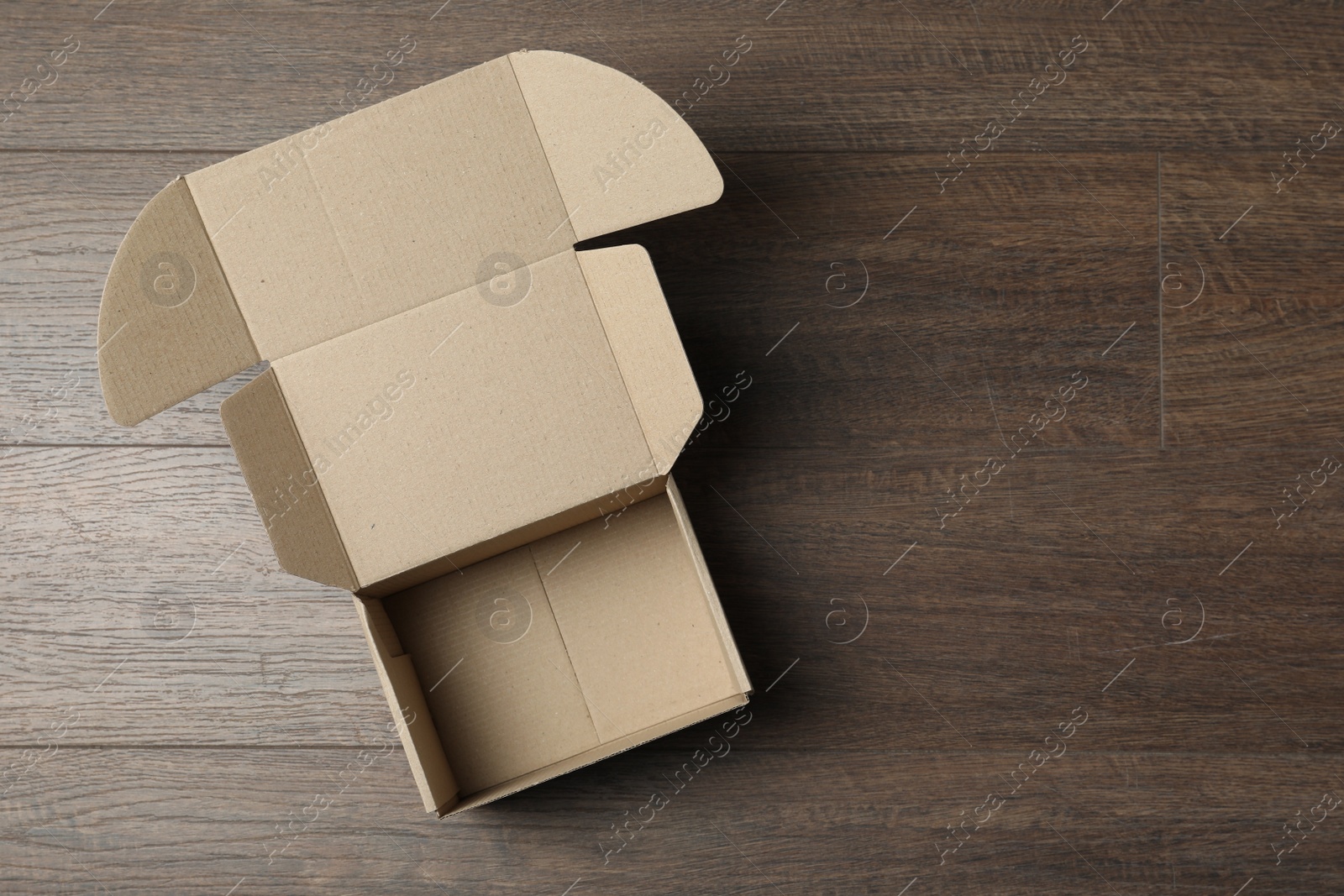 Photo of Empty open cardboard box on wooden table, top view. Space for text