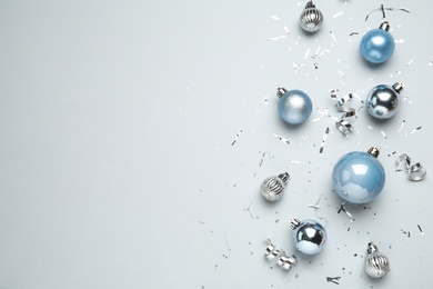 Photo of Flat lay composition with shiny Christmas balls, confetti and streamers on light background, space for text