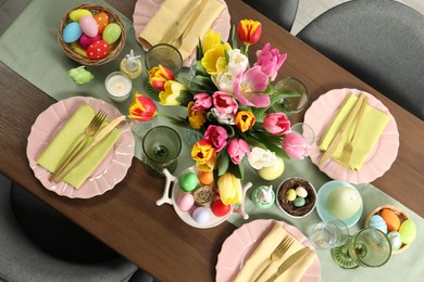Photo of Festive Easter table setting with beautiful flowers and painted eggs, top view