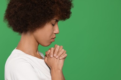 Photo of Woman with clasped hands praying to God on green background. Space for text