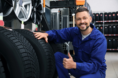 Male mechanic with car tires in auto store