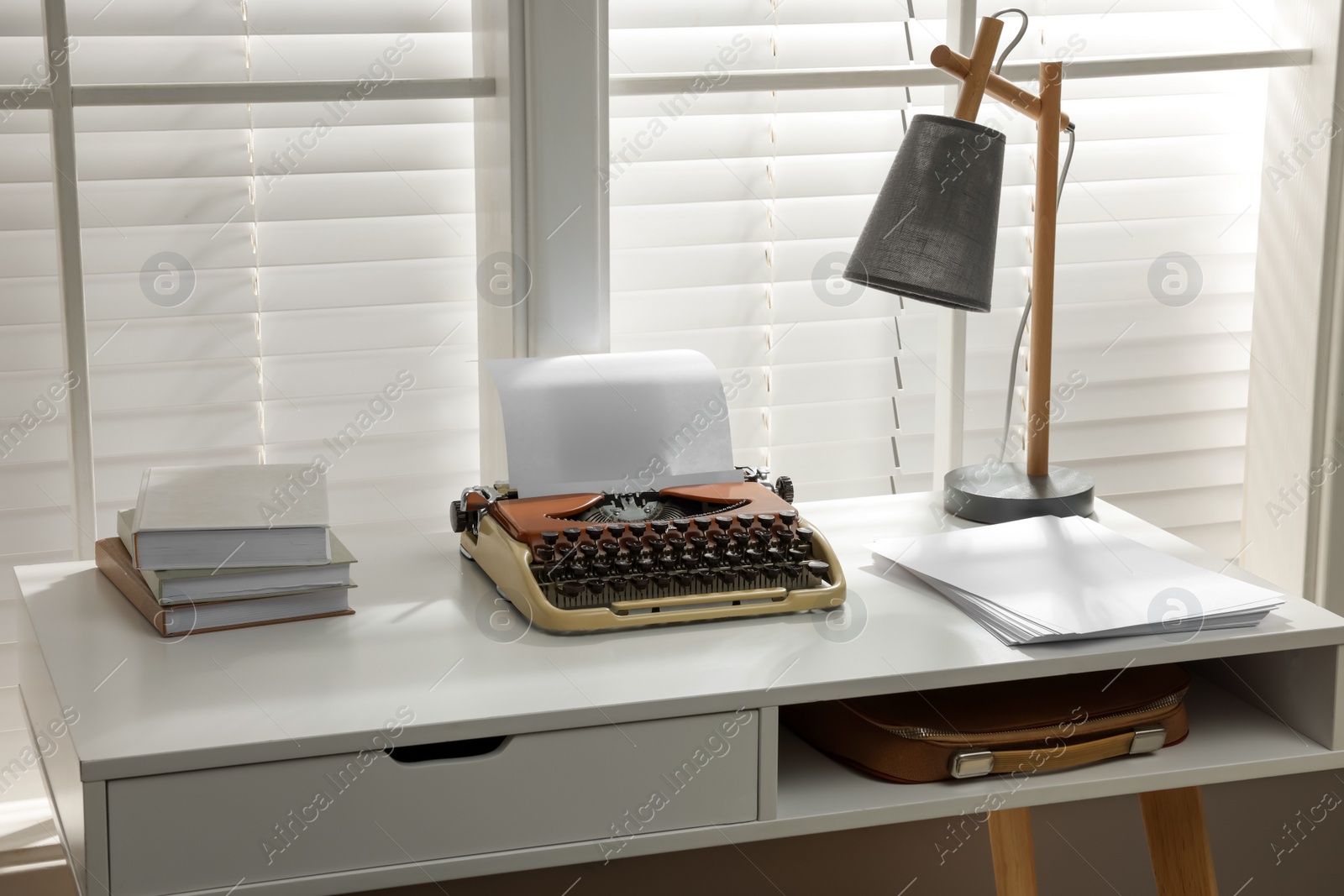 Photo of Comfortable writer's workplace with typewriter on desk in front of window