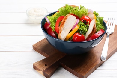 Photo of Delicious salad with chicken and vegetables on white wooden table