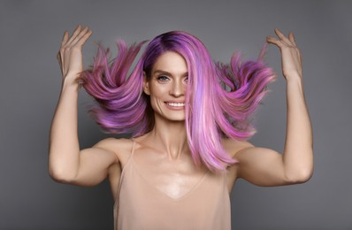 Hair styling. Gorgeous woman with colorful hair on grey background