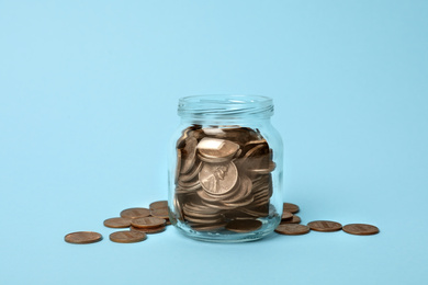 Photo of Glass jar with coins on light blue background