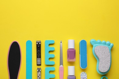 Set of pedicure tools on yellow background, flat lay. Space for text