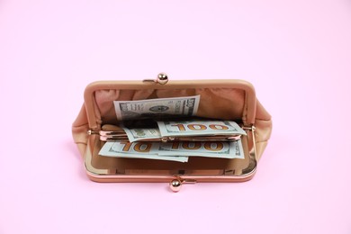 Stylish beige leather purse with dollar banknotes on pink background, closeup