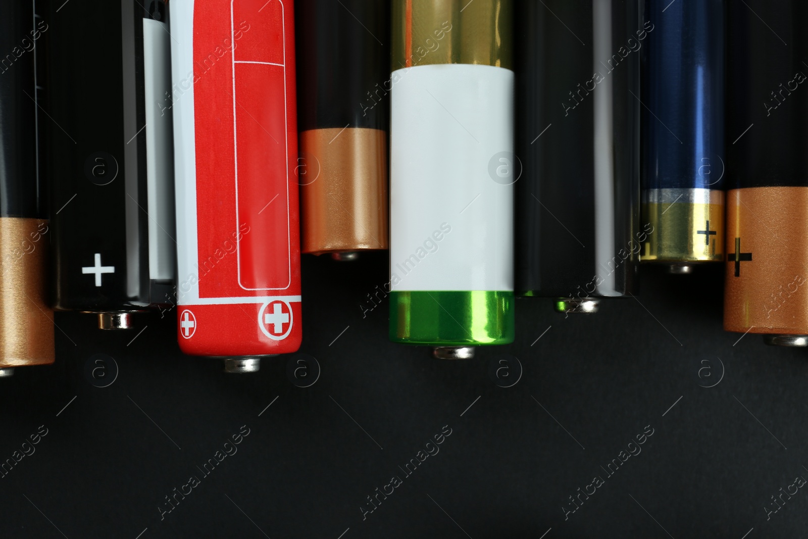 Image of Many different batteries on black background, flat lay