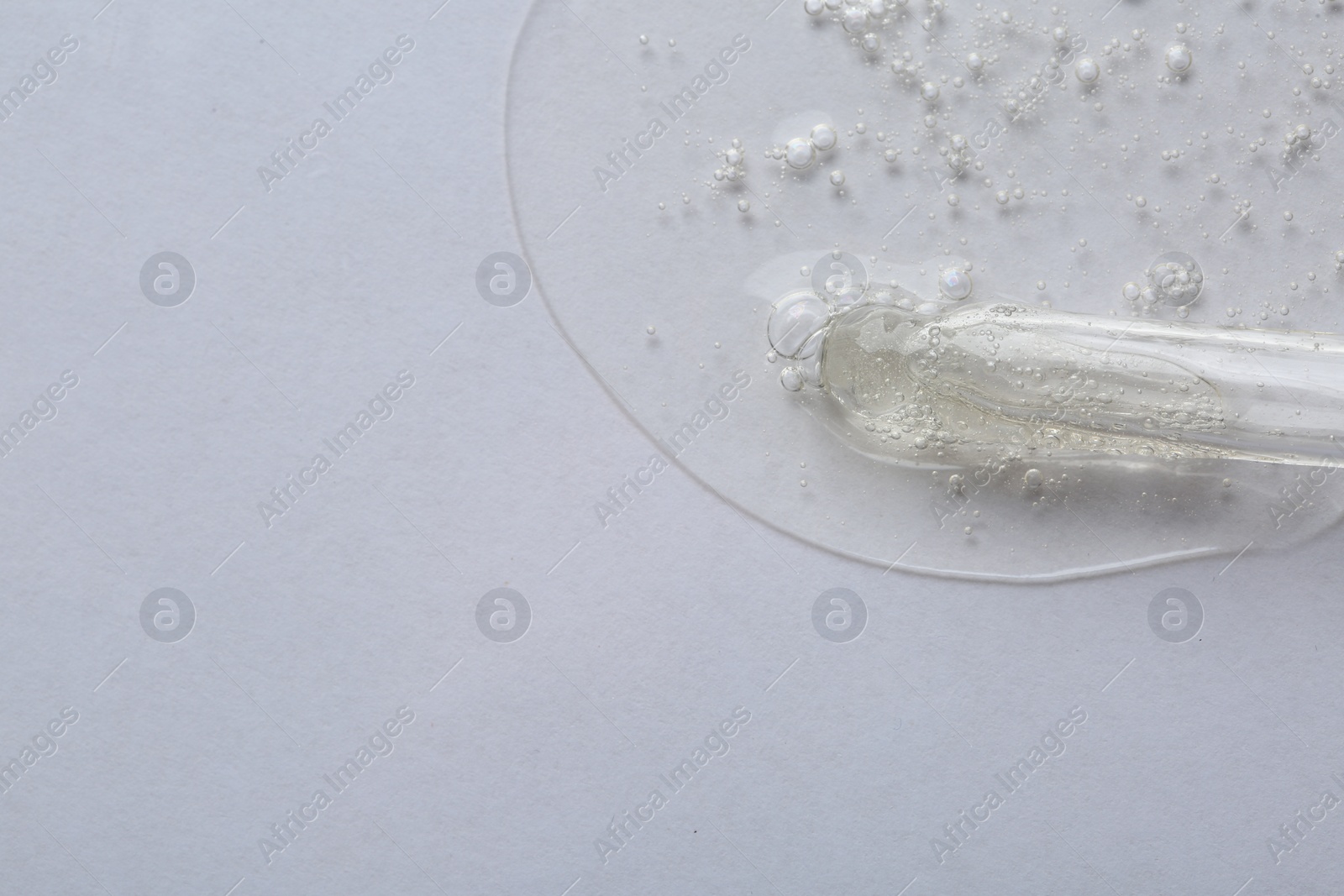 Photo of Pipette with cosmetic serum on white background, macro view. Space for text