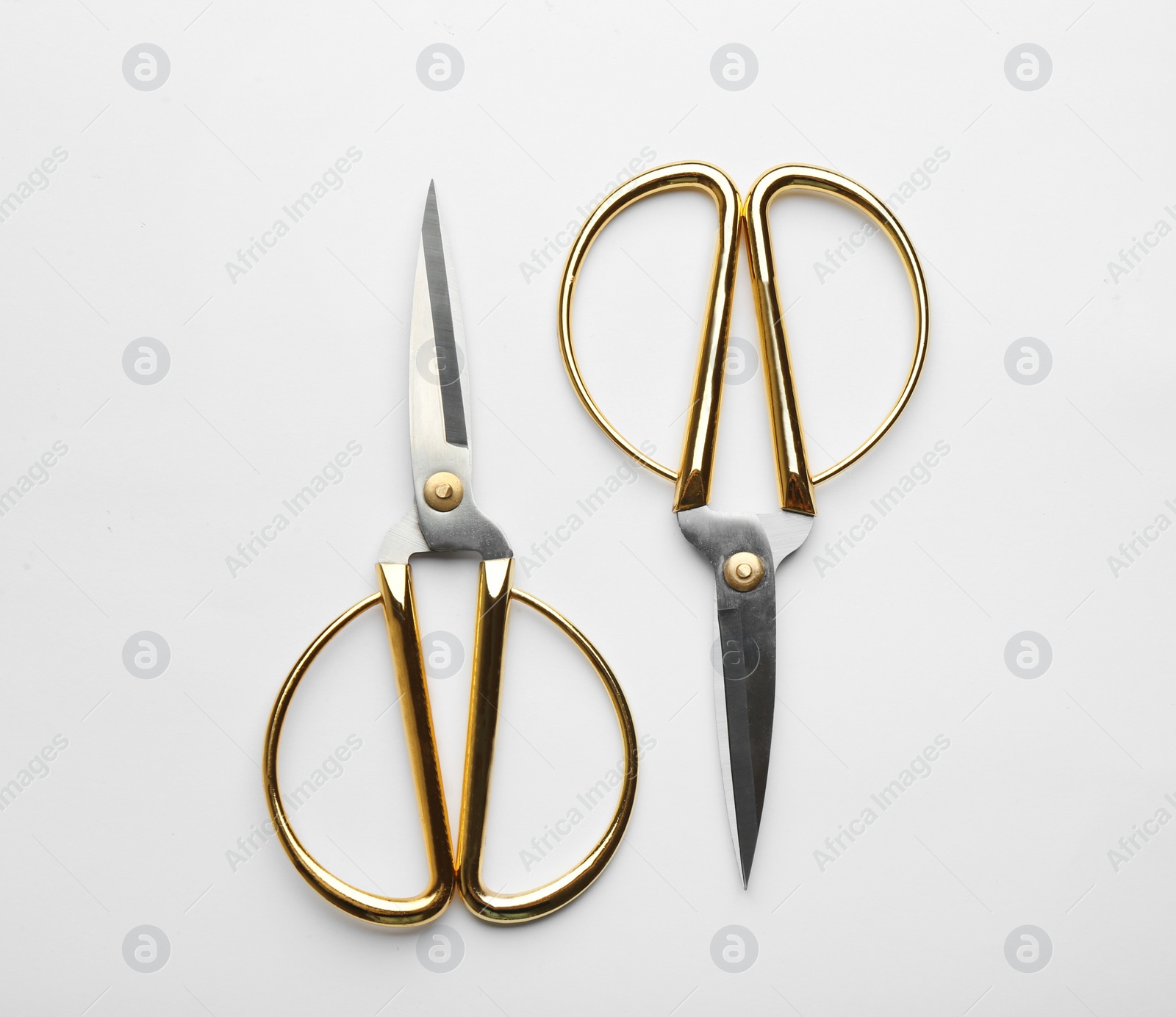 Photo of Scissors with golden handles on white background, top view