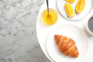 Photo of Delicious breakfast with croissant and honey on white table, top view. Space for text