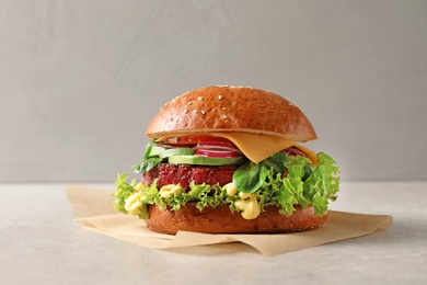 Photo of Tasty vegetarian burger with beet cutlet on table against light background