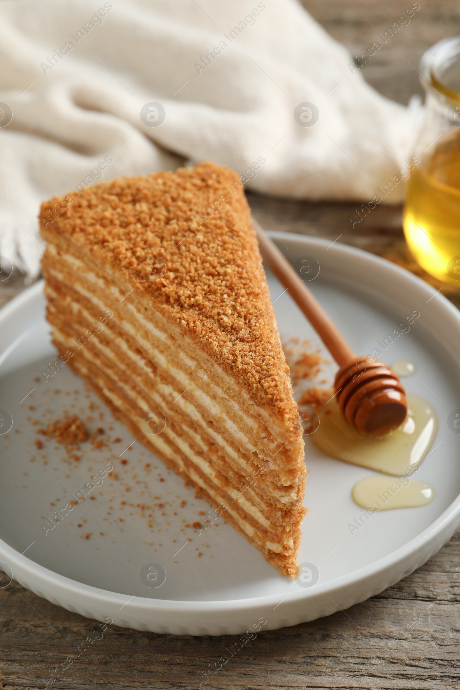 Photo of Slice of delicious layered honey cake served on wooden table, closeup