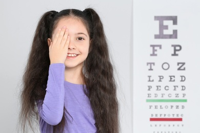 Photo of Cute little girl visiting children's doctor, space for text. Eye examination