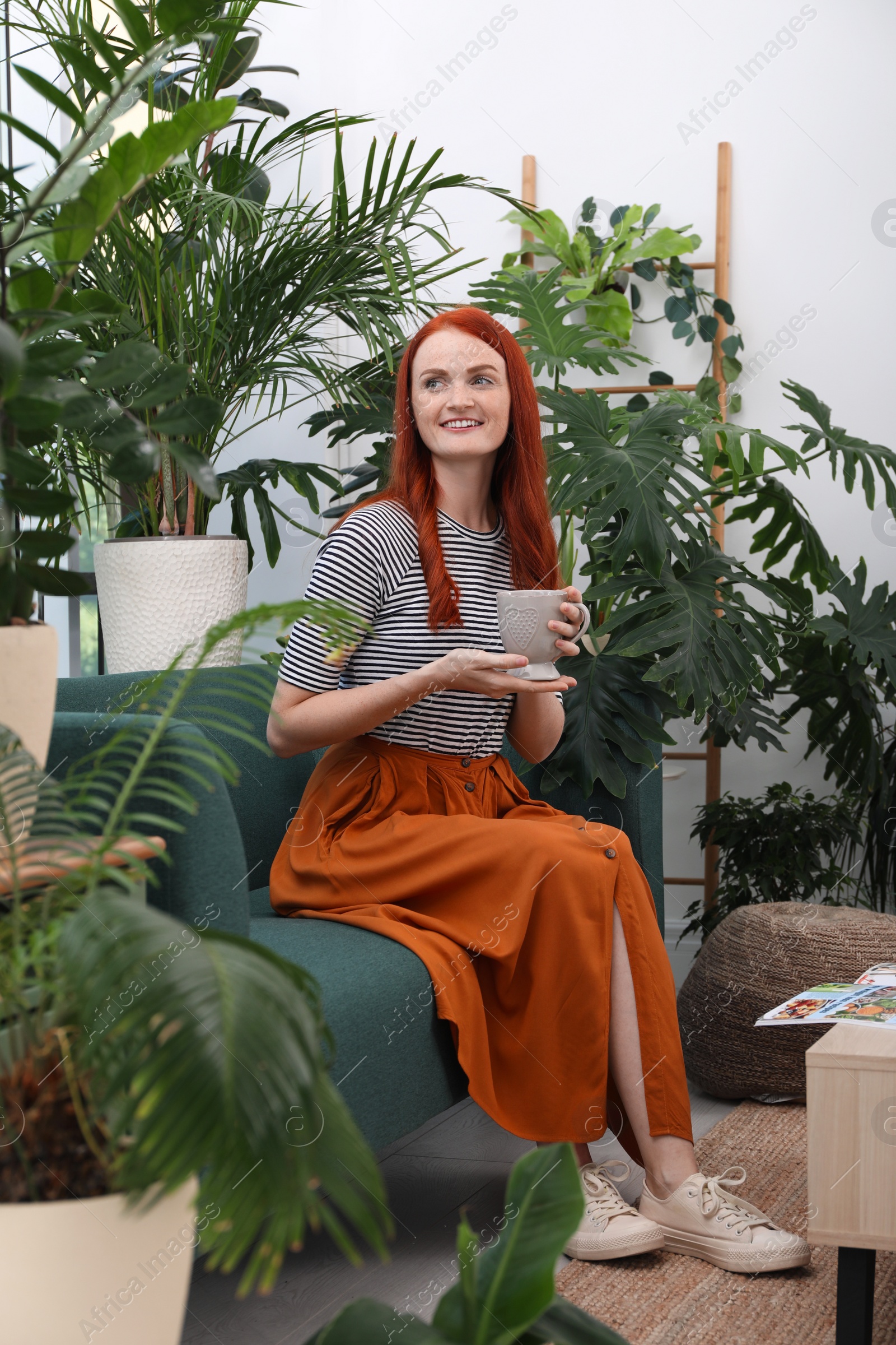 Photo of Beautiful woman with cup of tea resting on sofa in room