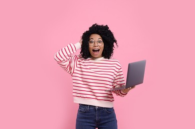 Photo of Emotional young woman with laptop on pink background