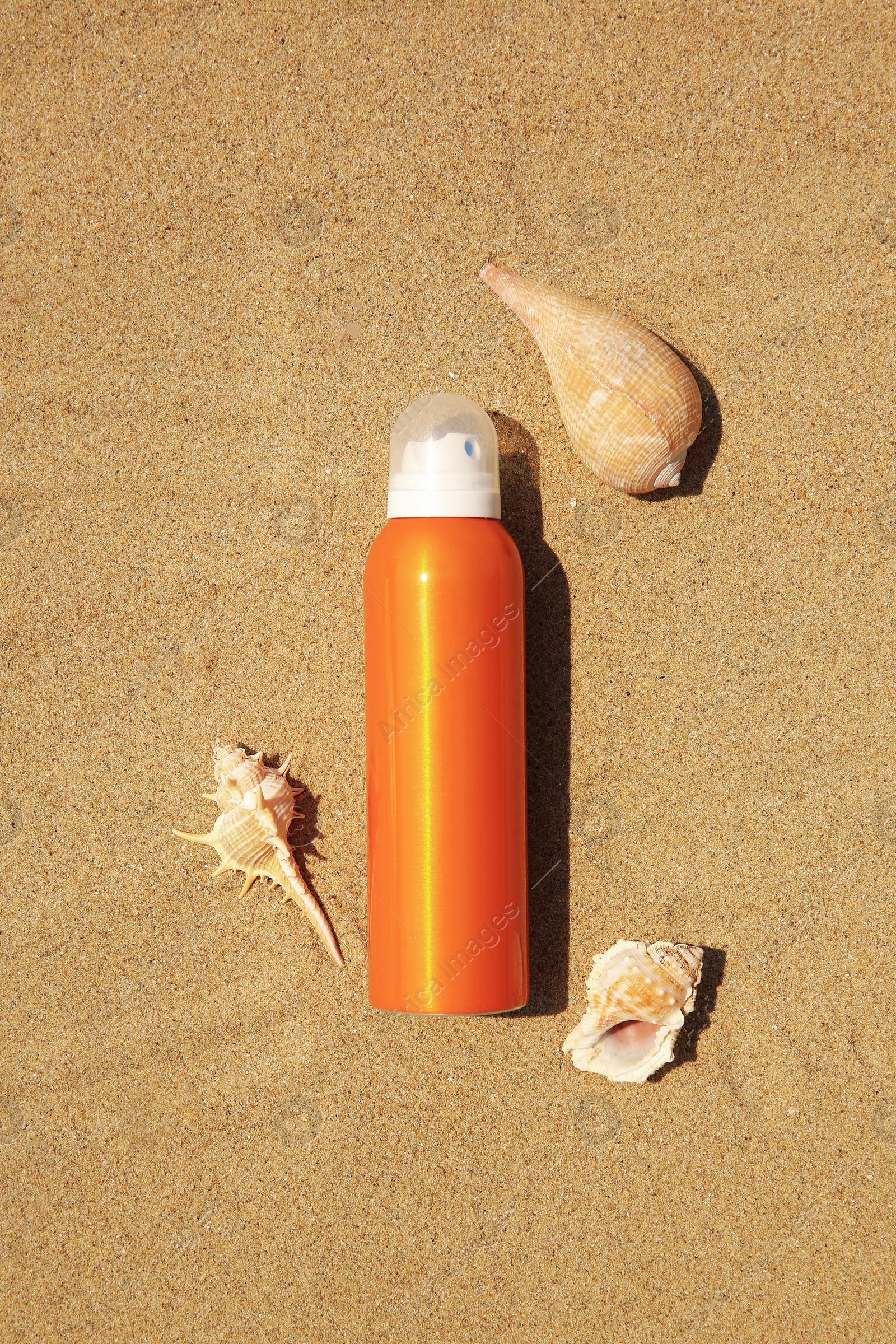 Photo of Sunscreen and seashells on sand, flat lay. Sun protection care