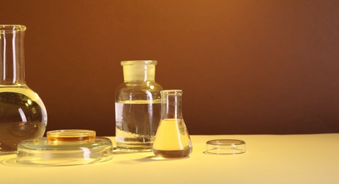 Laboratory analysis. Different glassware on table against brown background, space for text