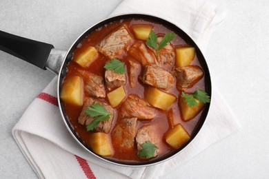 Photo of Delicious goulash in saucepan on light grey table, top view