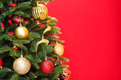 Photo of Beautiful Christmas tree with fairy lights and festive decor on red background