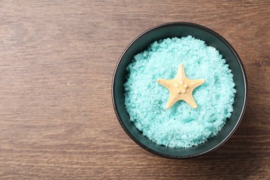 Light blue sea salt and starfish in bowl on wooden table, top view. Space for text