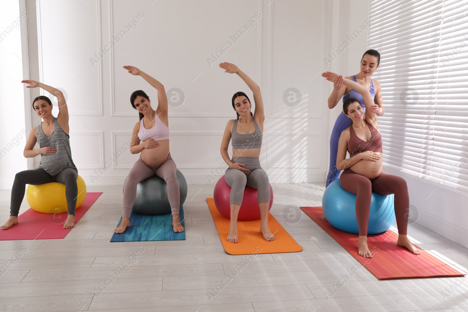 Photo of Trainer working with group of pregnant women in gym. Preparation for child birth