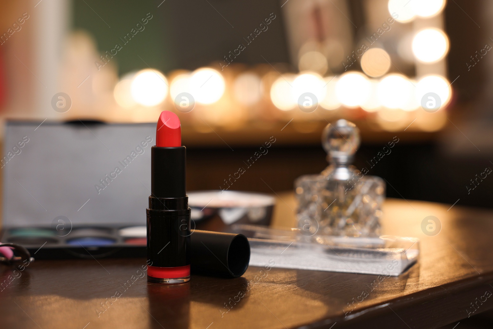 Photo of Red lipstick and other beauty products on wooden table. Makeup room