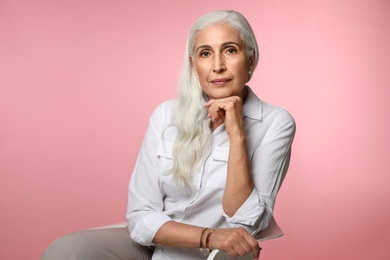 Portrait of beautiful mature woman on pink background