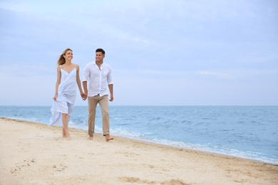 Happy couple having romantic walk on beach. Space for text