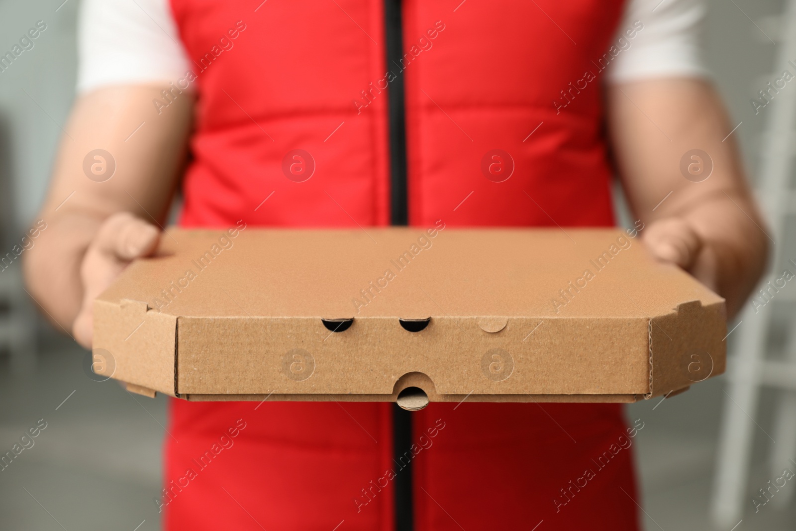 Photo of Man with pizza box indoors, closeup. Food delivery service