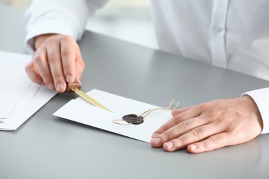 Male notary removing seal from document at table, closeup