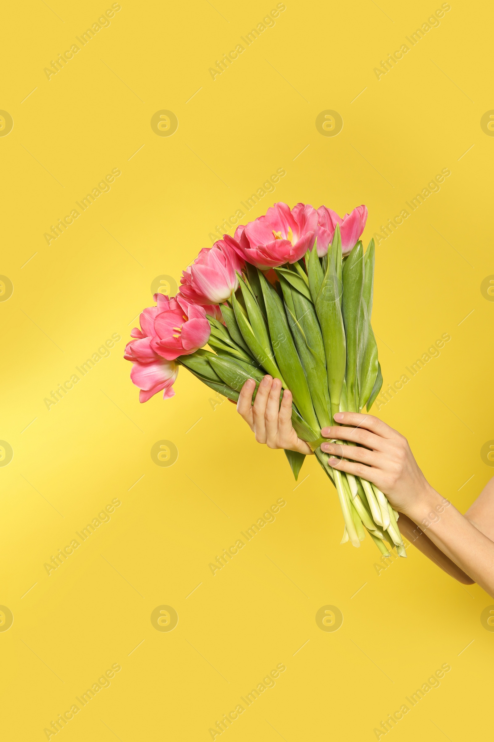 Photo of Girl with spring tulips on yellow background, closeup. International Women's Day