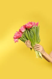 Girl with spring tulips on yellow background, closeup. International Women's Day