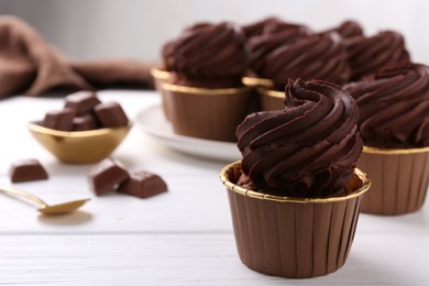 Delicious chocolate cupcake on white wooden table, closeup