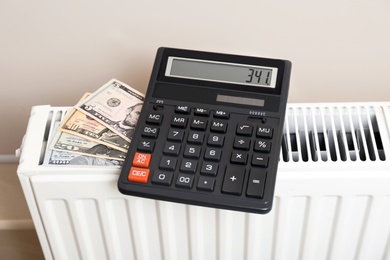 Calculator and money on heating radiator indoors