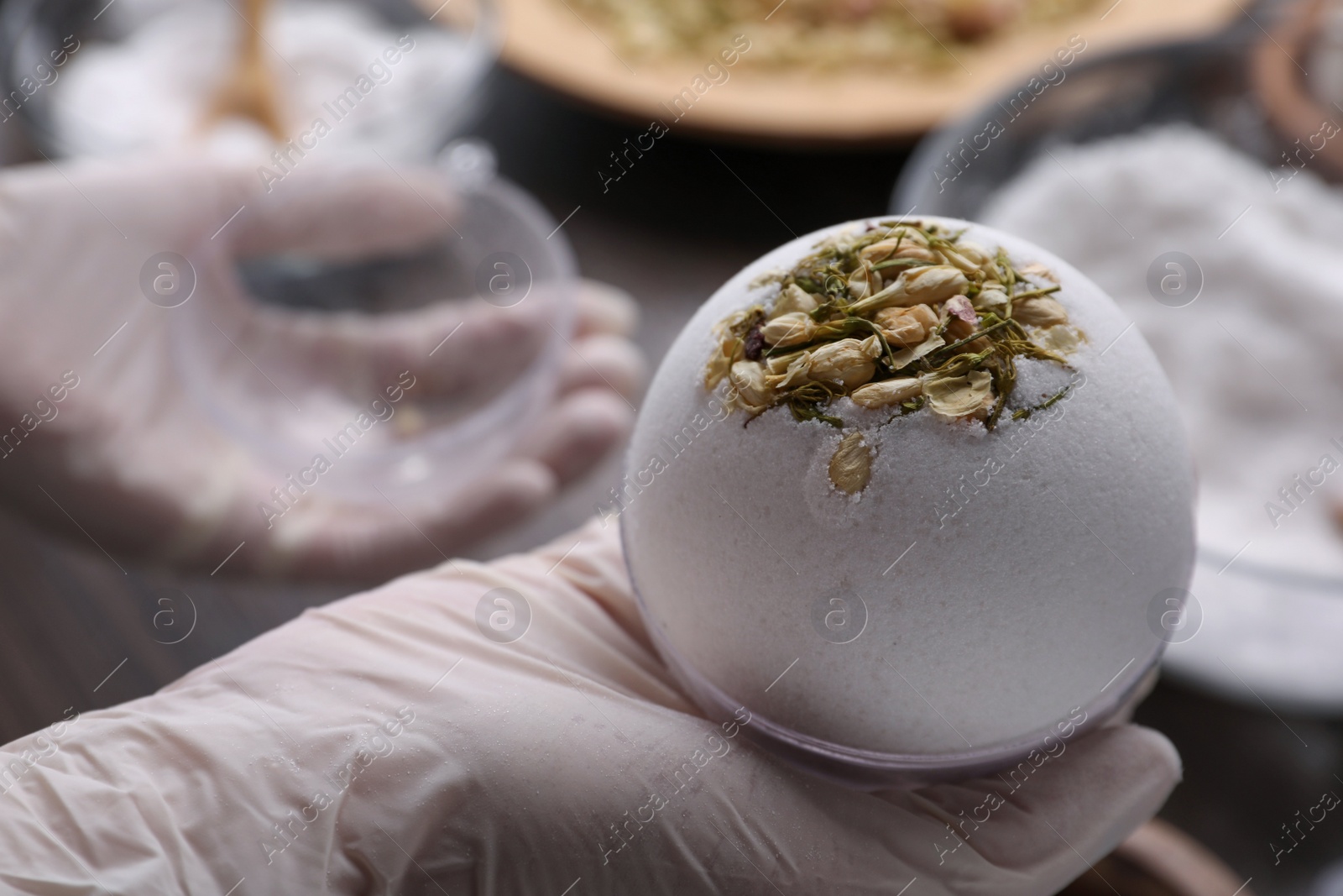 Photo of Woman in gloves making bath bomb at table, closeup