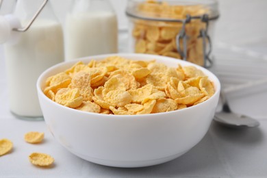 Photo of Tasty crispy corn flakes in bowl on white table, closeup. Breakfast cereal