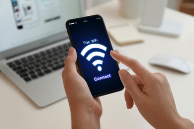 Image of Woman connecting to WiFi using mobile phone at table, closeup