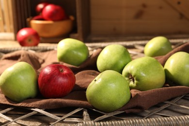 Photo of Fresh colorful apples on brown cloth and rattan grid